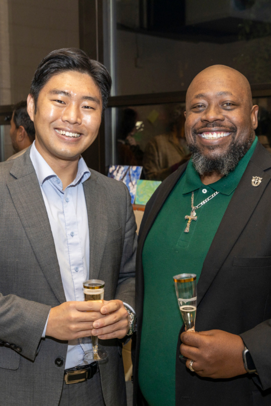 Two people smile at the camera holding champagne glasses