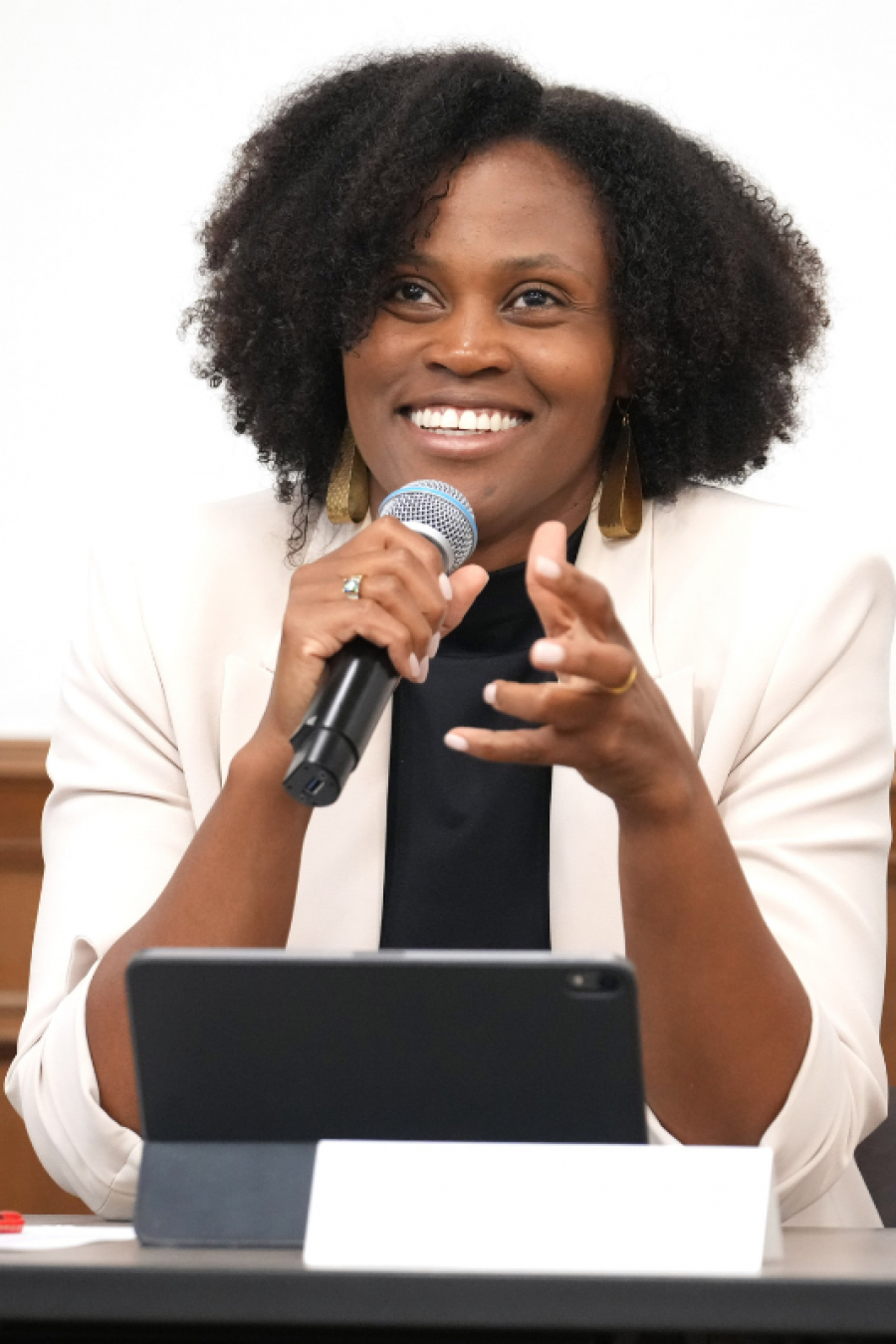 A person smiles and holds a microphone as they talk